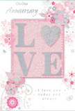 This anniversary card is a gentle study in enduring romance, echoing the calm charm of Hampton Hill's tree-lined avenues. At its centre, the word LOVE stands out in soft, raised glitter, the letters delicately textured and edged with silver so they shimmer just enough to catch the eye without overwhelming the design. The letter O is replaced by a sparkling heart, filled with brighter silver texture that suggests a precious keepsake, like a cherished piece of jewellery. Around this central element, a cloud of blush and mauve blooms unfurls across the card, painted with an almost watercolour softness that allows colours to melt into one another-powder pink, dusty rose, and gentle grey. Their fine, flowing outlines and soft shading evoke the feel of a romantic English spring garden, the sort of palette often chosen for anniversary bouquets delivered around Hampton Hill. Tiny finishing touches-airy petals, curling swirls, and subtle butterflies-give the design motion and lightness, as though a breeze were passing through. The background is a calm pastel pink, providing warmth while letting the silver details and florals shine. Interwoven with the artwork, the phrases On Our Anniversary and I love you today and always are written in an understated, graceful script, their careful curves mirroring the arc of stems and vines. The overall composition feels intimate and considered, like a hand-written note tucked beside a vase of fresh flowers on a sideboard. It is a paper keepsake that mirrors the tender thought behind an anniversary flower delivery in Hampton Hill, soft-spoken yet deeply heartfelt.